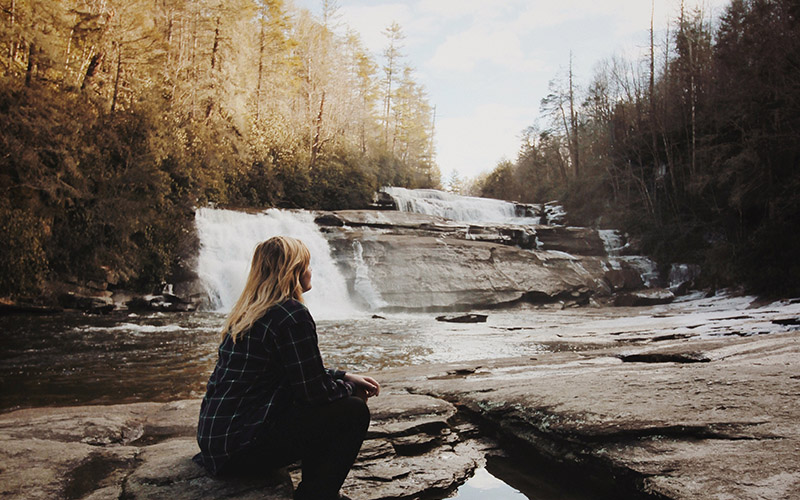 Woman sitting by waterfall